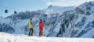 Zwei Skifahrer mit Blick auf verschneite Berge in Damüls-Mellau.