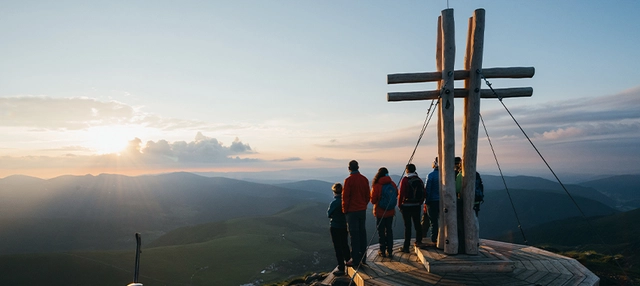 Eine Gruppe von Personen am Gipfel bei Sonnenaufgang in Kärnten.