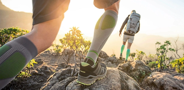 Fokusierte Wandersocke während des Sonnenuntergangs beim Wandern.