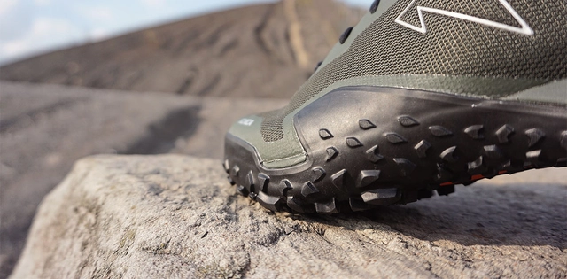 Schuhe_Zustiegschuhe_Hero_C-TimoDillenberge Dunkelgrüner Zustiegschuh auf Felsen mit nahmen Fokus auf die Sohle.