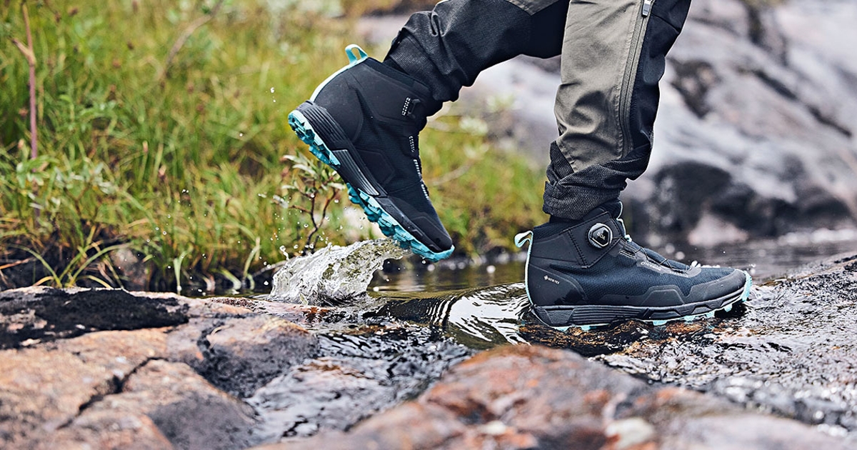 Leichter Schuh in schwarz blau während einer Wanderung über Steine durch ein Bachbett. 