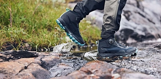Leichter Schuh in schwarz blau während einer Wanderung über Steine durch ein Bachbett. 