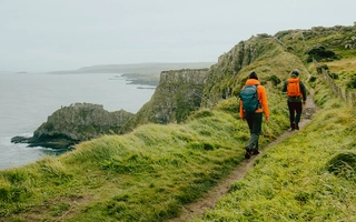 Zwei Personen beim Wandern an einer Küste in Nordirland.