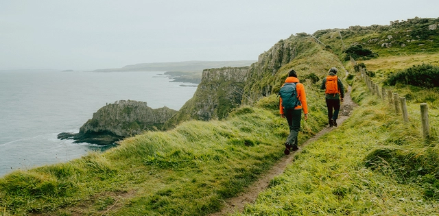 Inspirationen_Advertorial-Nordirland_Hero_C-JanaMargareteSchuler Zwei Personen beim Wandern an einer Küste in Nordirland.
