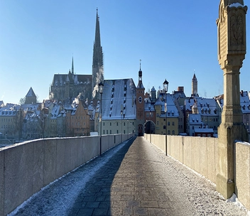 Brücke in Regensburg mit Gebäuden im Hintergrund.
