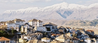 Mehrere Häuser mit Berglandschaft im Hintergrund in Albanien.