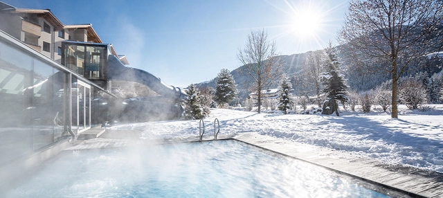 Außenpool der Dolomiten Residenz****s Sporthotel Sillian bei Schnee und Sonnenschein.