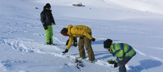 Aufnahme von Personen, die Gegenstände im Schnee betrachten.