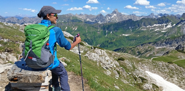 Eine Person mit Panoramaaussicht auf Bergkulisse in den Allgäuer Alpen.