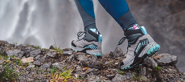 Leichter Treckingschuh von Scarpa in grau vor einem Wasserfall.