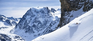 Skifahrer im Tiefschnee vor Bergpanorama.