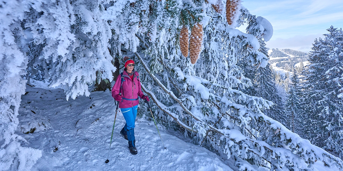 Eine Person beim Wandern in einer verschneiten Winterlandschaft in Balderschwang.