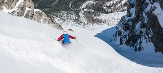 Aufnahme eines Skifahrers zwischen Bergen in Richtung Tal in Tirol.