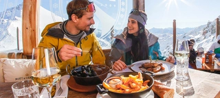 Zwei Personen beim Essen auf einer Skihütte in der Skiregion Hochzillertal-Kaltenbach.