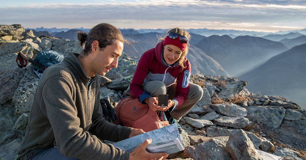 Zwei Wanderer auf dem Gipfel mit Landkarte und Kompass.