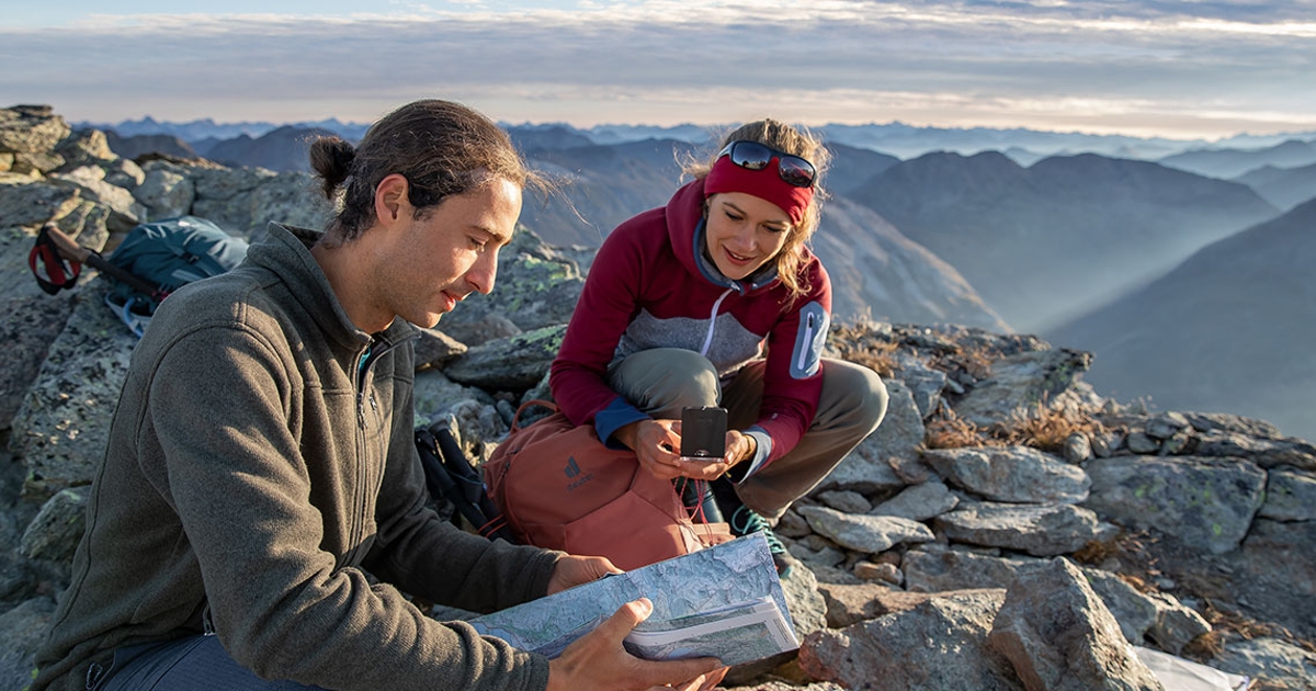 Zwei Wanderer auf dem Gipfel mit Landkarte und Kompass.