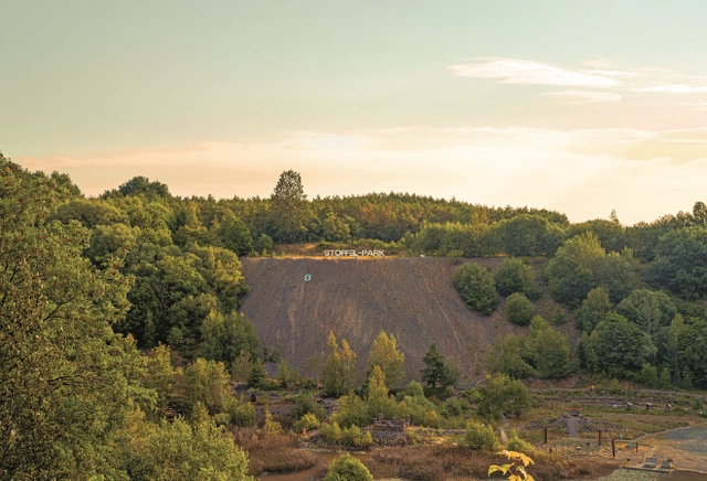 9.png Blick auf einen Erdwall mit dem Schriftzug Stöffelpark darauf