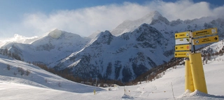 Aufnahme aus dem Skigebiet mit Wegweisern vor schneebedeckten Bergen im Aostatal.