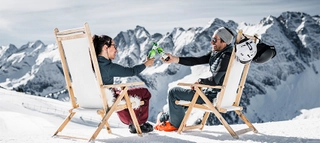 Zwei Personen in Liegestühlen vor verschneiter Bergkulisse im Zillertal.