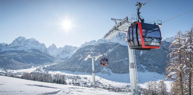 3ZinnenDolomiten_Hero_C-3ZinnenDolomiten-ChristianTschurtschenthaler Gondelbahn vor verschneitem Bergpanorama in der Region 3 Zinnen Dolomiten.