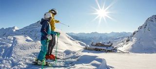 Zwei Personen auf Ski in der Skiregion Hochzillertal-Kaltenbach bei Sonnenschein.