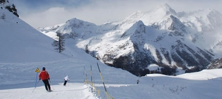 Skifahrer auf der Piste vor verschneiten Bergen im Aostatal.
