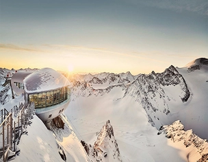 Gebäude am verschneiten Berg mit Sonnenschein im Hintergrund am Pitztaler Gletscher.