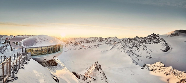 Gebäude am verschneiten Berg mit Sonnenschein im Hintergrund am Pitztaler Gletscher.