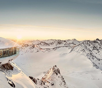 Gebäude am verschneiten Berg mit Sonnenschein im Hintergrund am Pitztaler Gletscher.