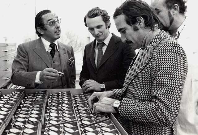 Jack Heuer (l.) erklärt den Rennsport-Assen Niki Lauda (2. v. l.) und Clay Regazzoni den Aufbau ihres goldenen Automatikchronographen.