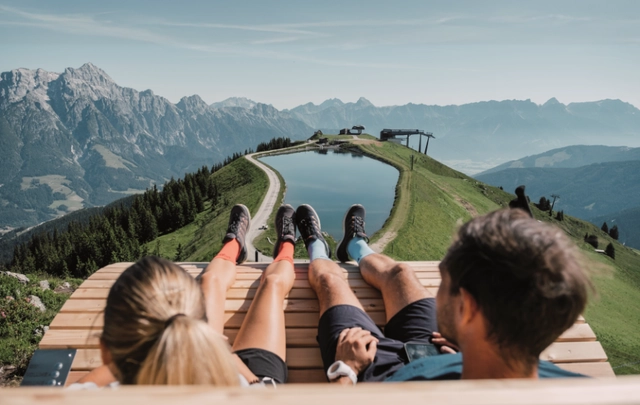 Zwei Personen sitzen auf einer Bank und genießen ein Bergpanorama