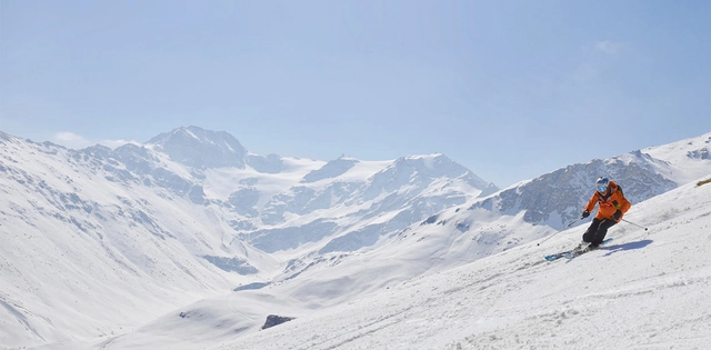 Skifahrer vor verschneiter Bergkulisse.