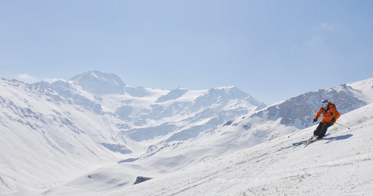 Skifahrer vor verschneiter Bergkulisse.