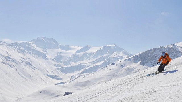 Skifahrer vor verschneiter Bergkulisse.