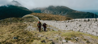 Zwei Personen beim Wandern vor Bergpanorama in Nordirland.