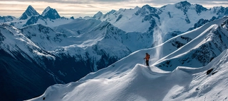Person vor tief verschneiter Bergkulisse in Kanada.