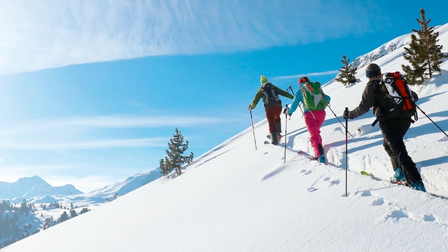 Skitourengeher während des Aufstiegs im Schnee bei schönem Wetter im Val Müstair.