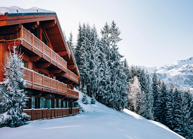 Außenansicht eines Chalets im Winter neben verschneiten Bäumen.