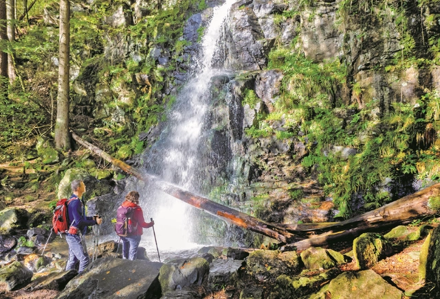 5.png Zwei Wanderer stehen vor einem Wasserfall
