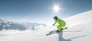 Skifahrer auf Piste bei Sonnenschein und blauem Himmel im Zillertal.