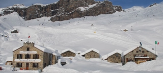Gebäude im Schnee mit verschneitem Berg und Skilift im Hintergrund im Aostatal.