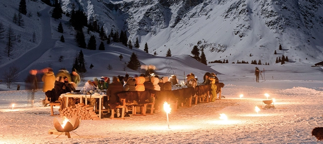 Gruppe von Personen, die bei Nacht an einem langen Tisch sitzen.