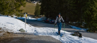 Skitourengeher neben Straße bei wenig Schnee in Tirol.