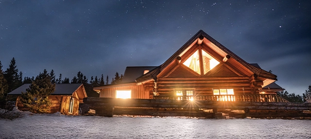Inspirationen_Heliskiing-Kanada_Bild5_C-BellaCoolaHeliSports-JesajaClass.jpg Beleuchtetes Gebäude im Winter bei der Terra Nostra Guest Ranch in Kanada.