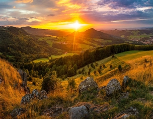 Weitblick auf die Landschaft mit Sonne am Horizont.