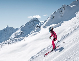 Skifahrerin auf Piste vor verschneiter Bergkulisse in Sölden.