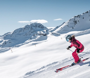 Skifahrerin auf Piste vor verschneiter Bergkulisse in Sölden.