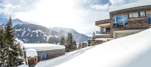 Chalet Deluxe im Gradonna Mountain Resort in Kals am Großglockner neben verschneiter Bergkulisse.