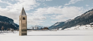 Der versunkene Turm im Reschensee bei Schnee im Winter.