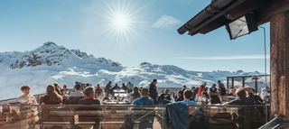 Einige Personen auf einer Terrasse im Skigebiet Silvretta Montafon bei Sonnenschein.